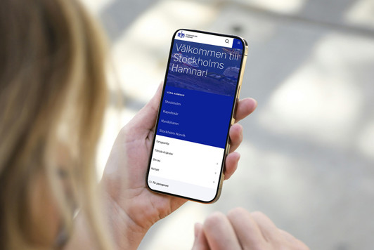 En person tittar på Stockholms Hamnars nya webbplats i sin mobil.