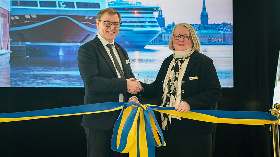 Sjöfartsverkets gd Erik Eklund och Stockholms Hamnars vd Magdalena Bosson skakar hand framför en stor blågul rosett.