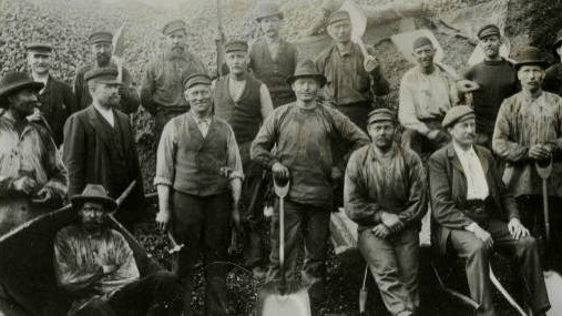 Stockholms kolbärare och gårdsarbetarelag vid Olaus Olssons kolgård vid Värtan. Ett stort antal män i arbetskläder - svartvit bild