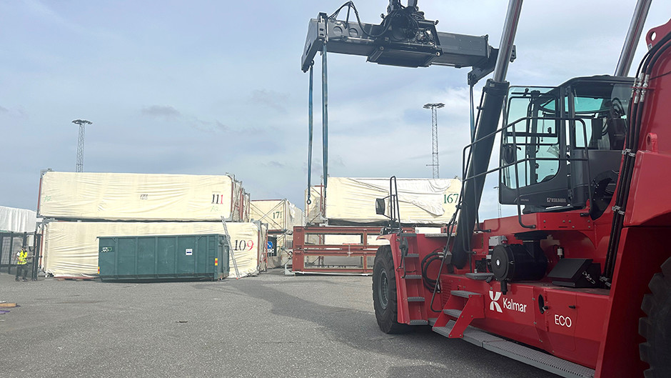 Containertruck plockar upp en husmodul från kajen i Frihamnen.