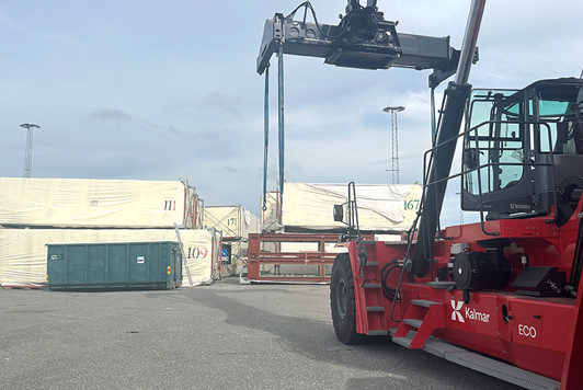 Containertruck plockar upp en husmodul från kajen i Frihamnen.