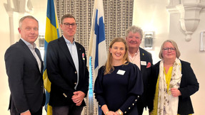 Talare på sjöfartsträffen står framför en svensk och en finsk flagga.