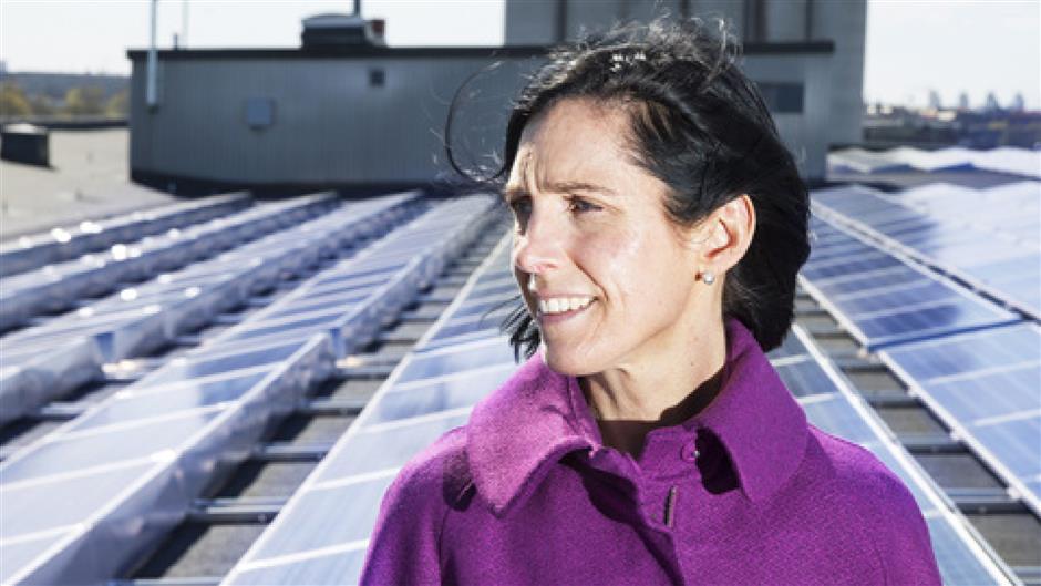 Lena Ekbom står bland solpanelerna på taket till Magasin 6 i Frihamnen.
