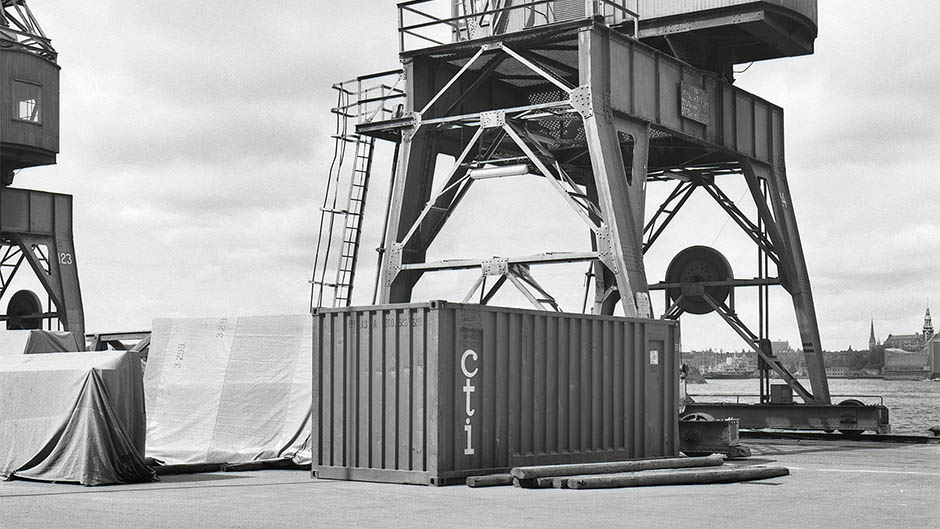 Svartvit bild på gammal container vid containerkran