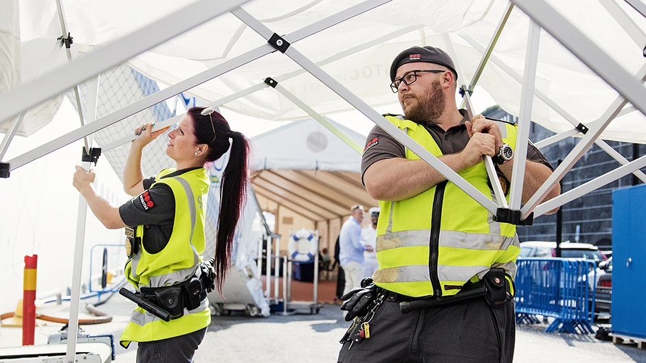 Tolga med kollega sätter upp ett tält inför en säkerhetskontroll