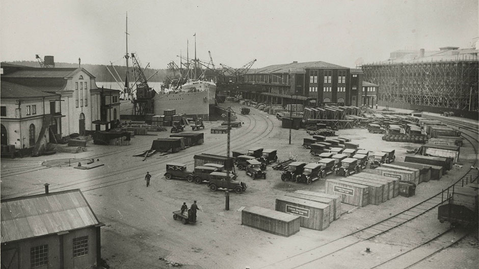 Bilar, förpackade i lådor och i färdigt skick lagrade på planen väster om Magasin 2. 1926.