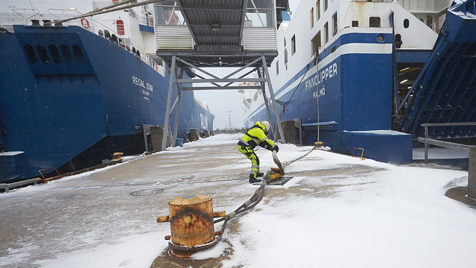 Hamnarbetare förtöjer roro-fartyg i snöigt Kapellskär