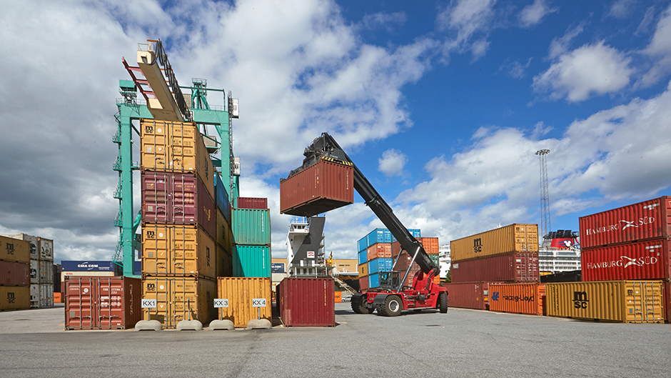 Containertruck lyfter upp en container i terminalen