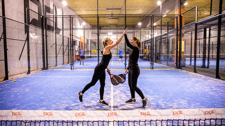 Två tjejer gör highfive på en padelbana