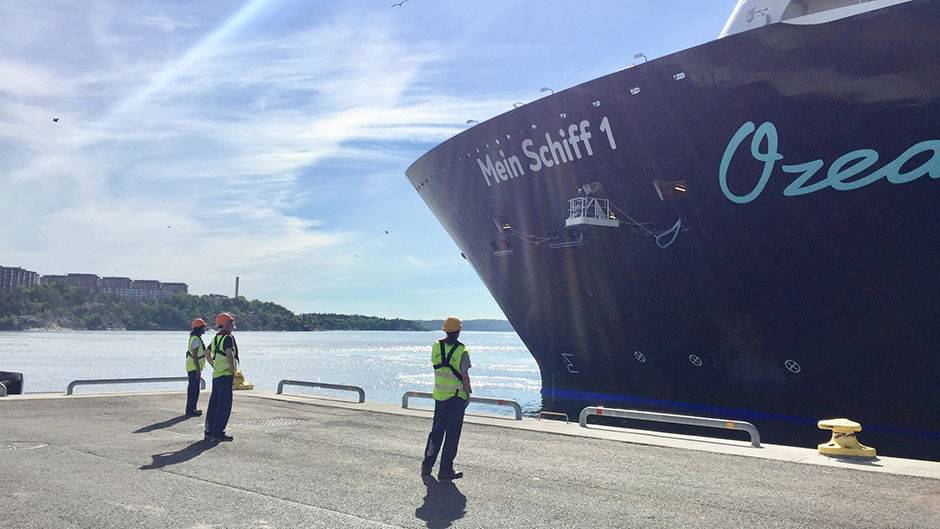 Fören på Mein Schiff 1 samt tre hamnarbetare som förtöjer henne i Frihamnen