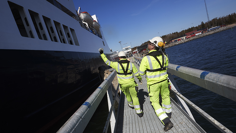 Två hamnarbetare i Kapellskärs hamn går längs med ett fartyg
