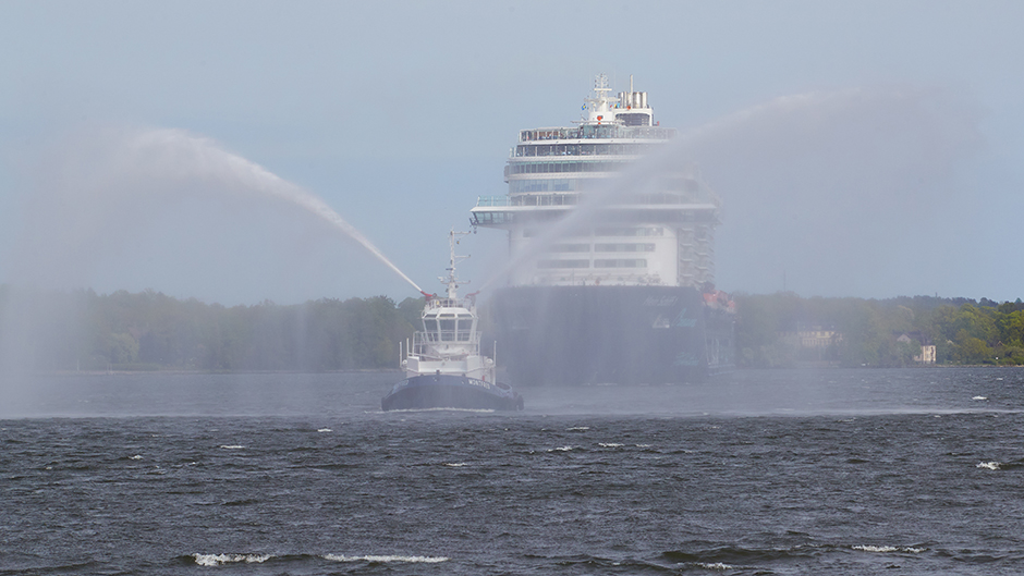 Bogserbåten Montfred vattensaluterar Main Schiff 1 på väg in i hamn