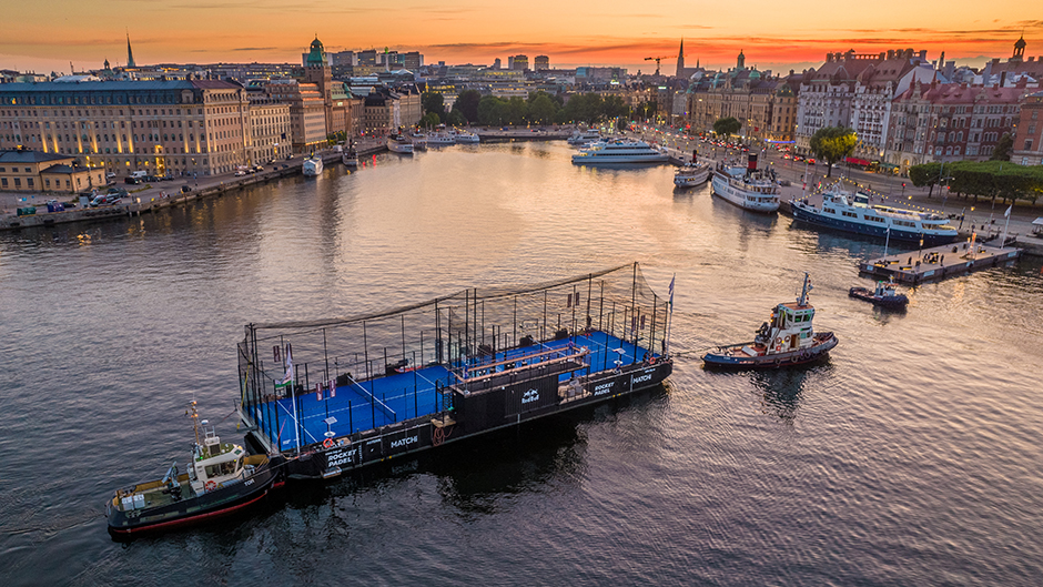 Padelpråm som bogseras på plats med Nybroviken i fonden