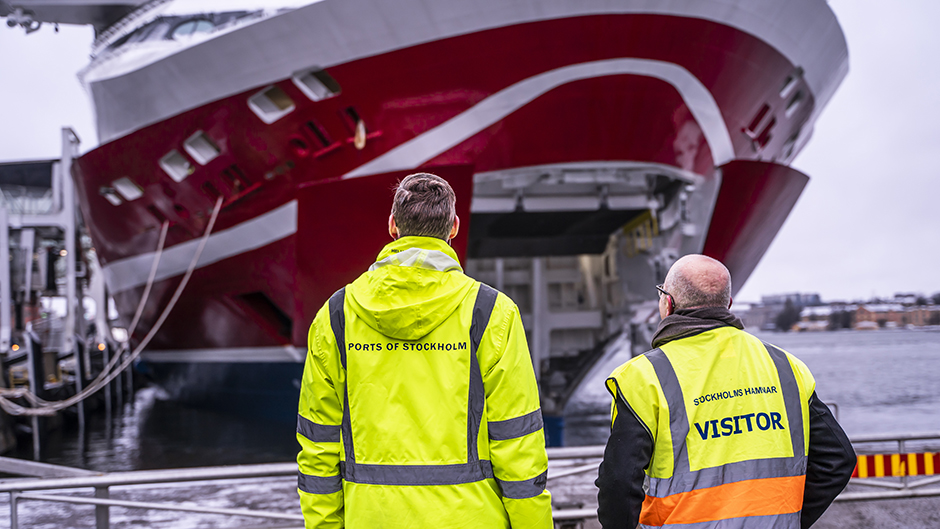 Två män i varselkläder framför Viking Glorys öppna bogport