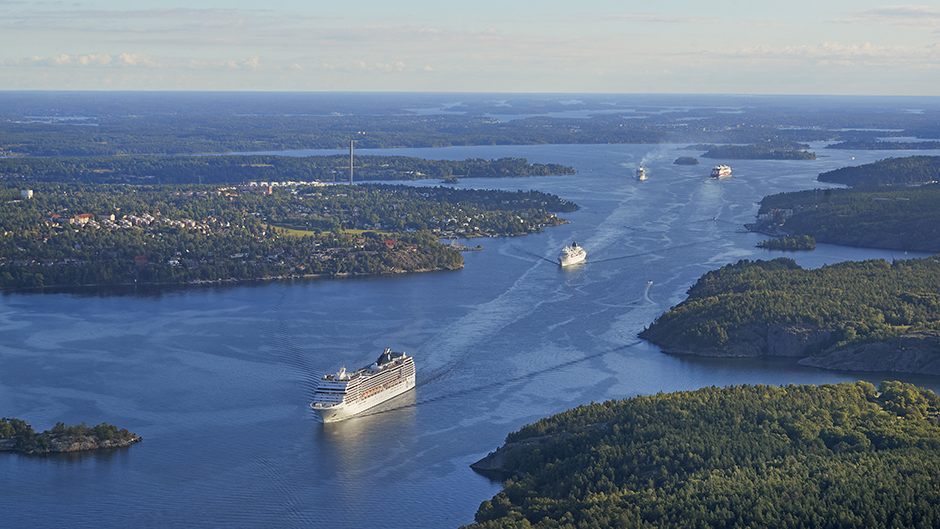 Flygbild över farleden in till Stockholm med ett pärlband av fartyg på väg in och ut